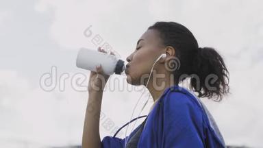 非洲裔美国跑步妇女跑步后<strong>饮水</strong>或等渗。 肖像健身妇女<strong>饮水</strong>瓶。